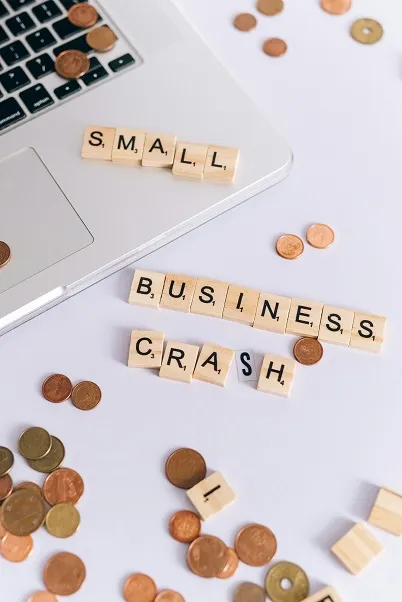 Illustration of small coins, a laptop and a cube-shaped inscription: small business crash. Symbolizes bankruptcy.