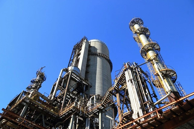 Industrial chemical plant with multiple tall towers and pipes under a clear blue sky. Illustrates the critical infrastructure sector.