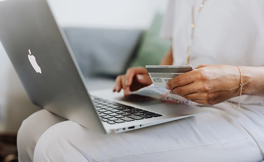 A photo of a person holding a laptop on their lap and a credit card in their hand. It illustrates the e-commerce industry.