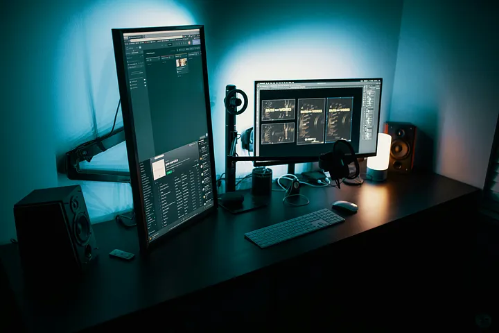 Computer setup with two screens, keyboard, mouse and speakers